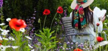 femme assise sur un banc dans son jardin fleuri